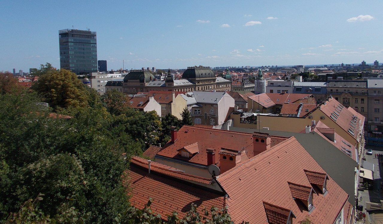 Вид с Верхнего города Загреба на красные черепичные крыши, купола зданий центра и высотку на горизонте