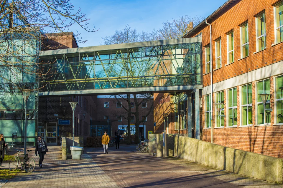 Glass skybridge between brick buildings above a pedestrian walkway