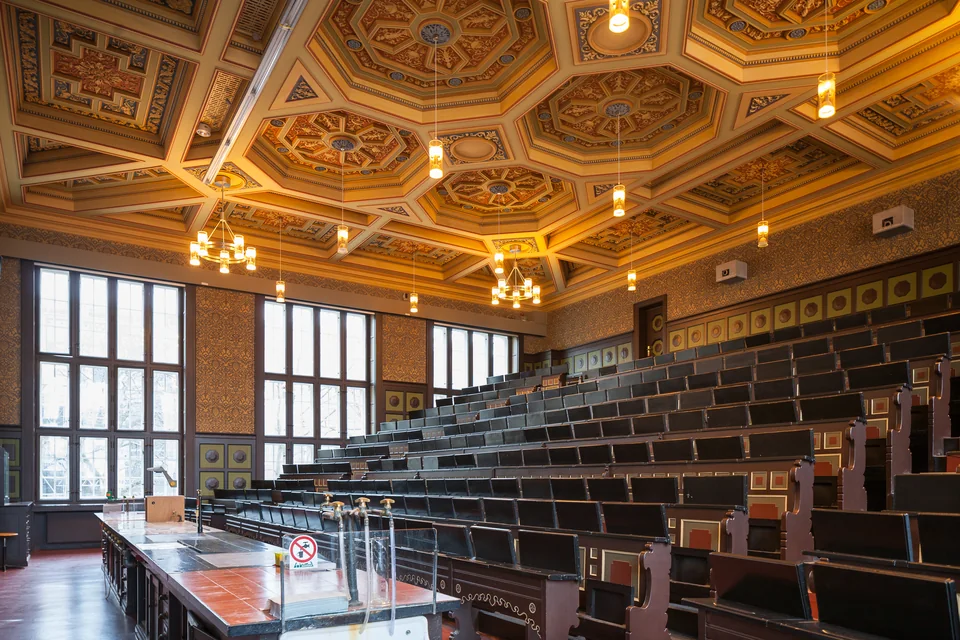 Пустая амфитеатровая аудитория с деревянными рядами, кессонным расписным потолком и люстрами в Ганноверском университете