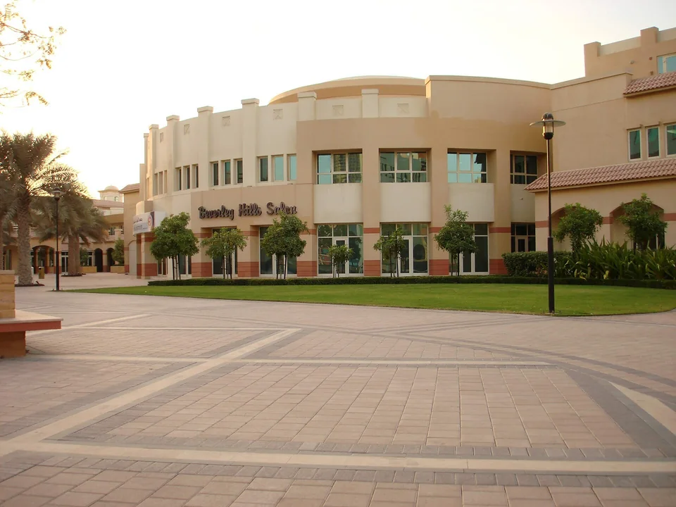 Площадь с газоном перед двухэтажным корпусом в Dubai Knowledge Park в мягком вечернем свете