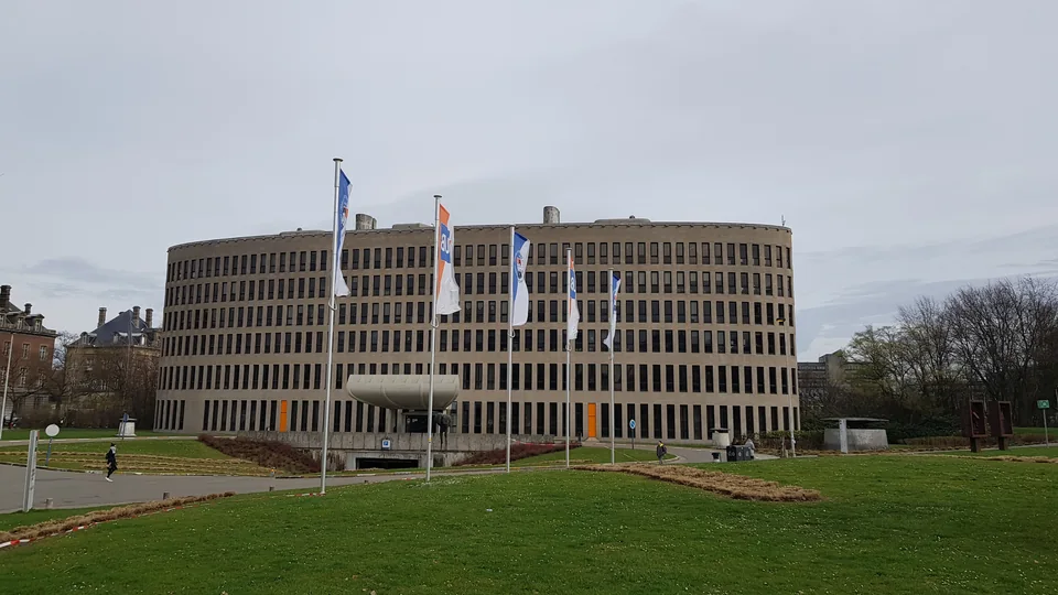Rounded multi-storey building with flagpoles in front of a lawn