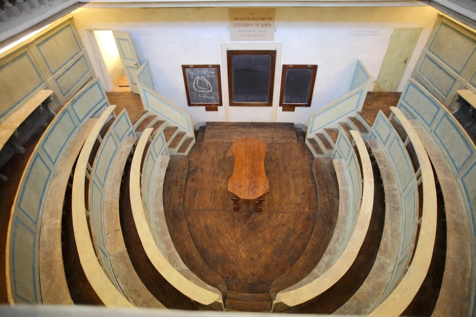 Overhead view of an oval anatomical theatre with wooden tiers and a table in the centre