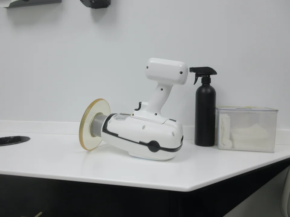 White handheld X-ray unit on a countertop beside a spray bottle and a box of cotton rolls