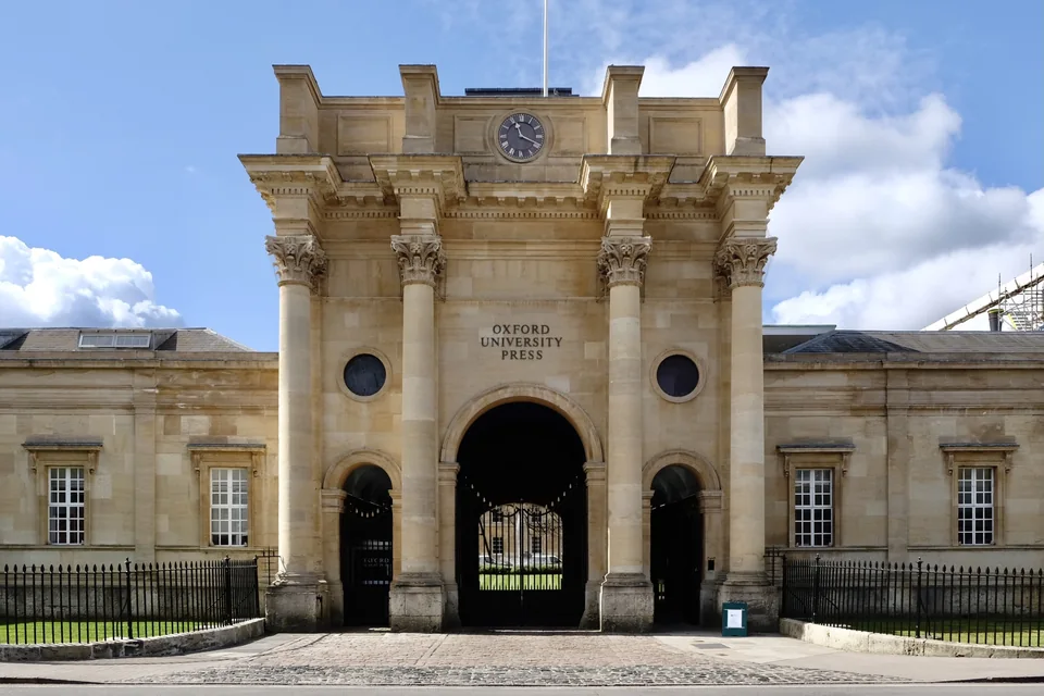 Фасад Oxford University Press с колоннами, часами и входной аркой
