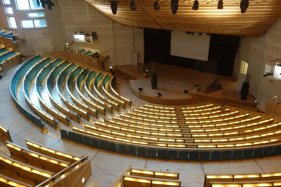Empty amphitheatre with curved rows of seats and a wooden ceiling