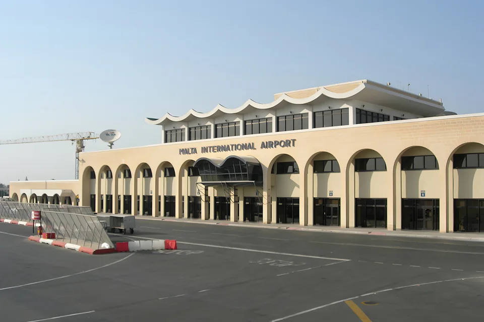 Светлое здание аэропорта с арочной галереей и надписью Malta International Airport