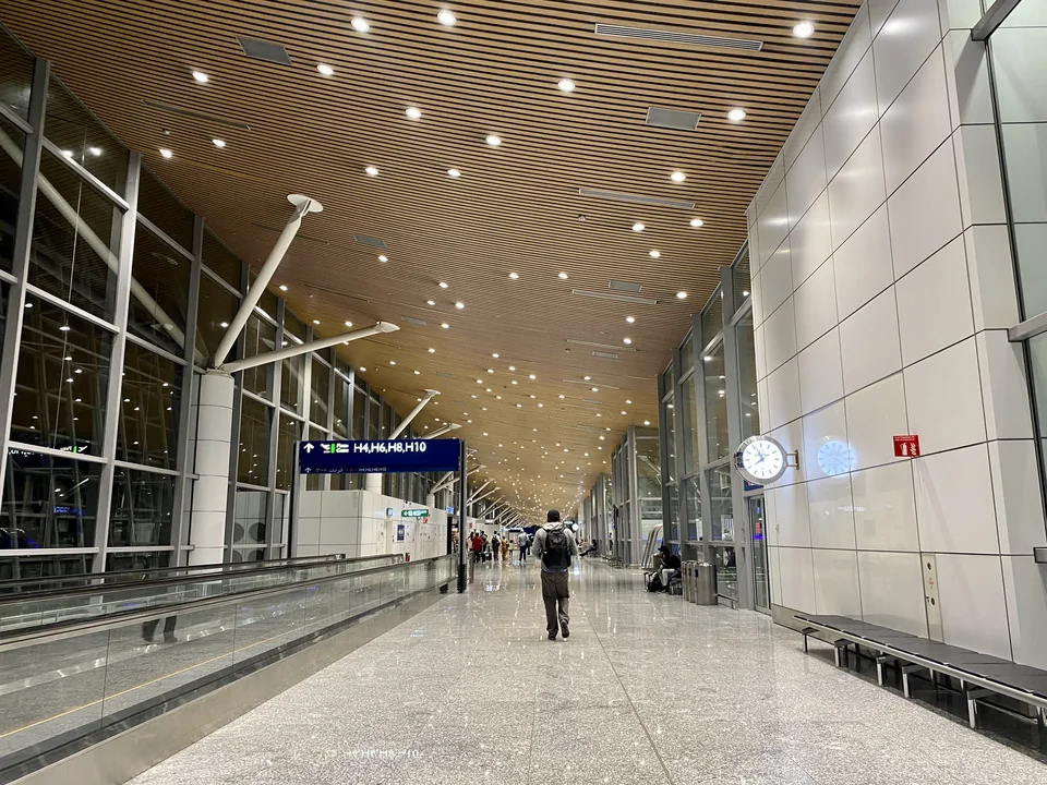 Long terminal corridor with a wooden ceiling, a moving walkway and a gate sign