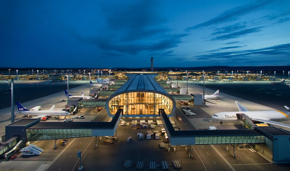 Lit terminal pier with aircraft at the jet bridges against a dusk sky
