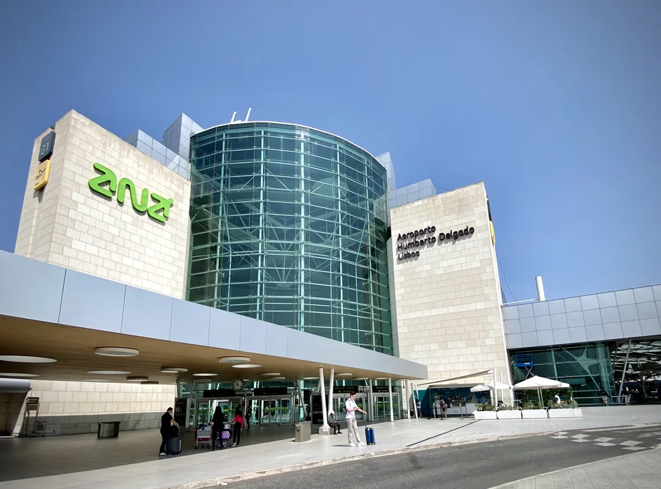 Glass cylindrical terminal entrance with a canopy and the Aeroporto Humberto Delgado sign