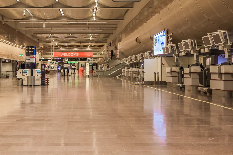 Empty departures hall with self-service check-in kiosks and a glossy floor
