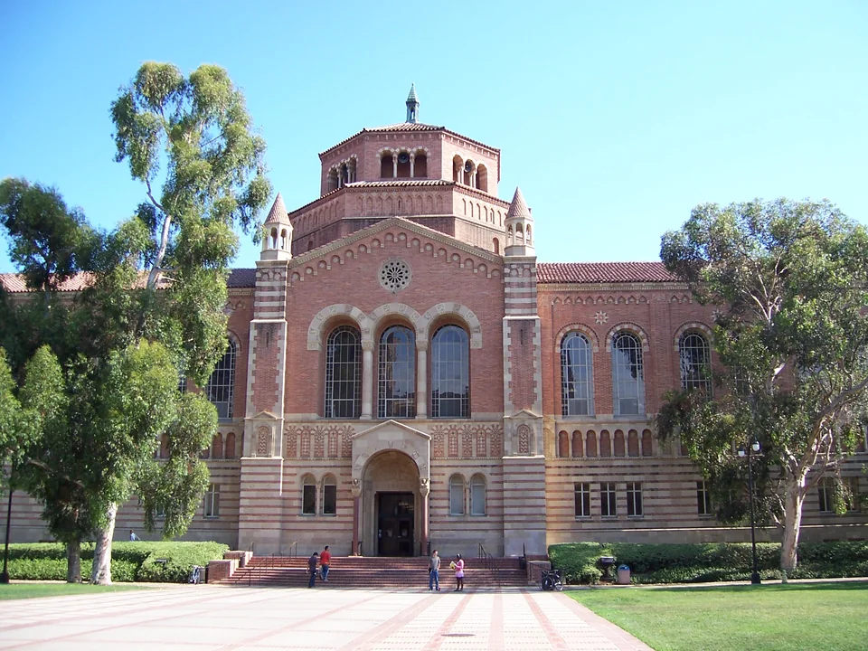 Краснокирпичная библиотека Пауэлла UCLA с восьмигранной башней и арочными окнами под ясным небом