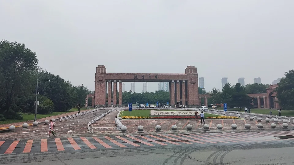 Кирпичные ворота с колоннадой и надписью иероглифами в конце площади с каменными шарами, по бокам деревья