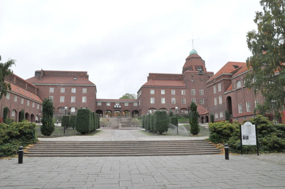 Red-brick buildings around a courtyard with steps and trimmed trees