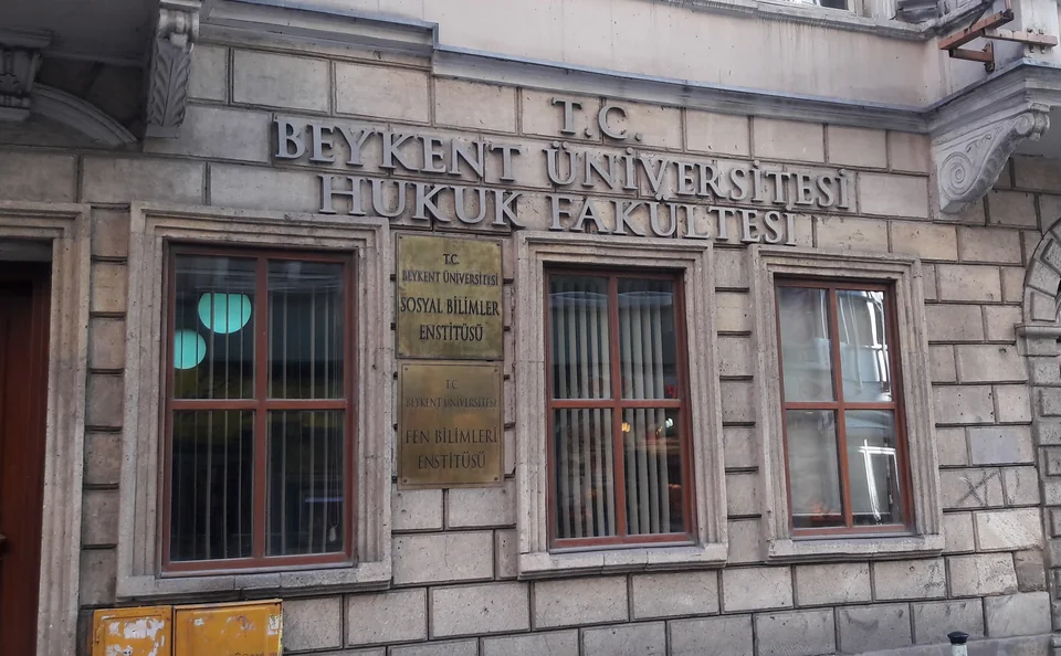 Каменный фасад с объёмной надписью T.C. Beykent Üniversitesi Hukuk Fakültesi, латунными табличками и окнами в рамах