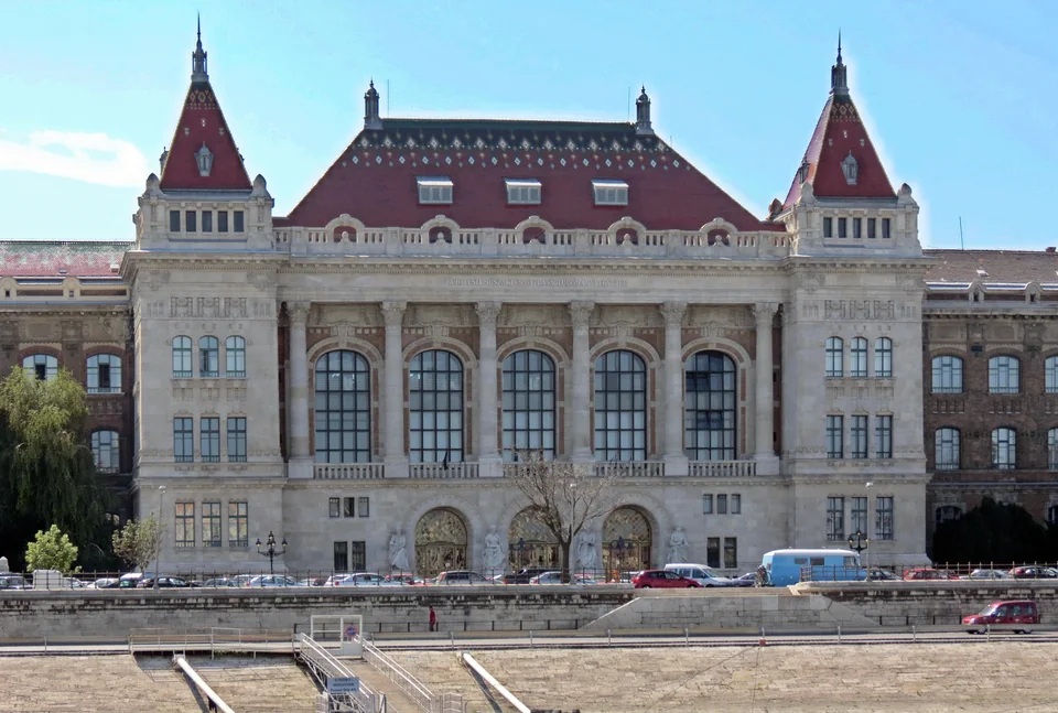 Eclectic façade with large arched windows and two turrets with patterned tile roofs
