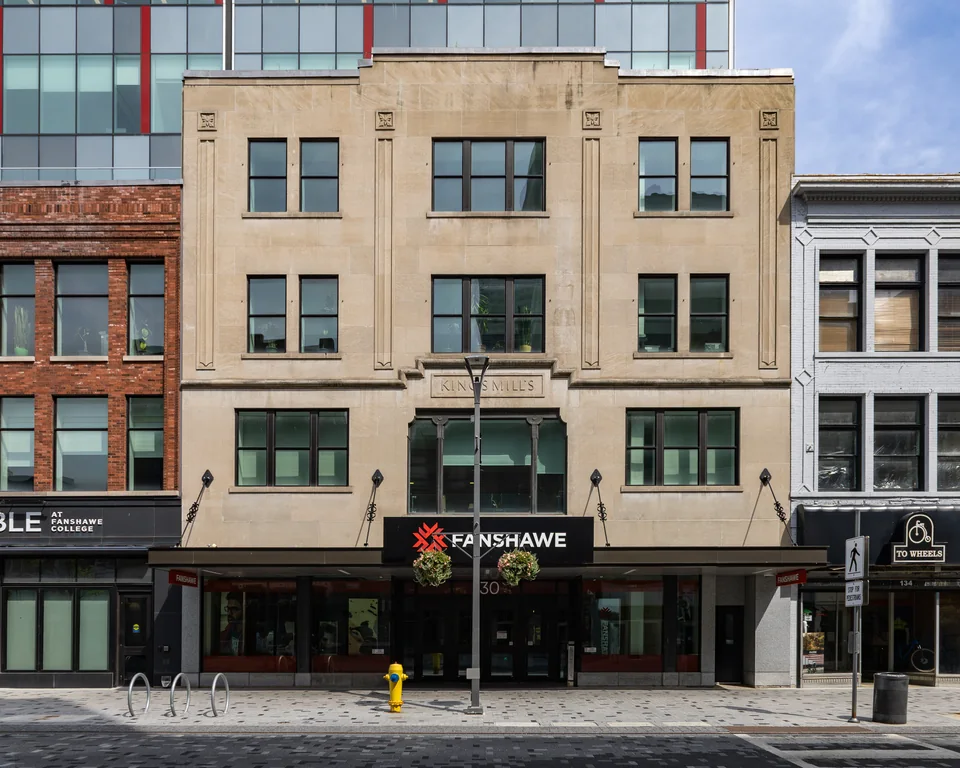 A four-storey stone façade with a canopy reading Fanshawe above the entrance, and a pavement with bicycle racks and a fire hydrant in front