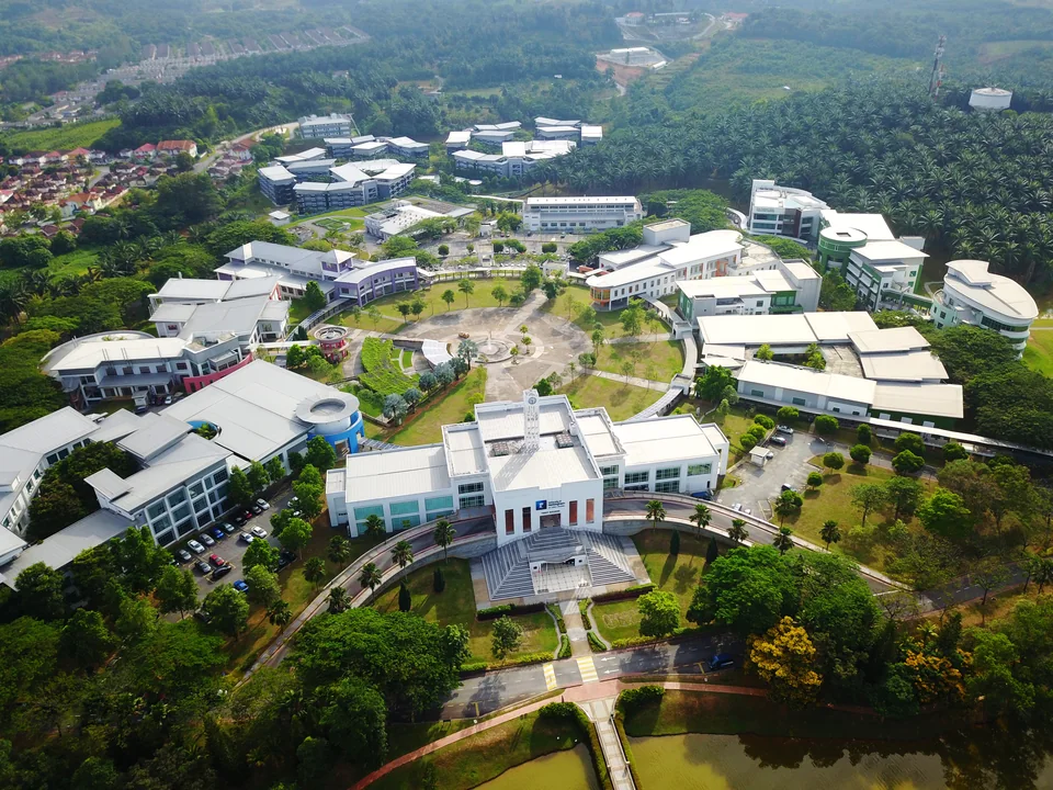 Aerial view of white campus buildings around a circular green among trees