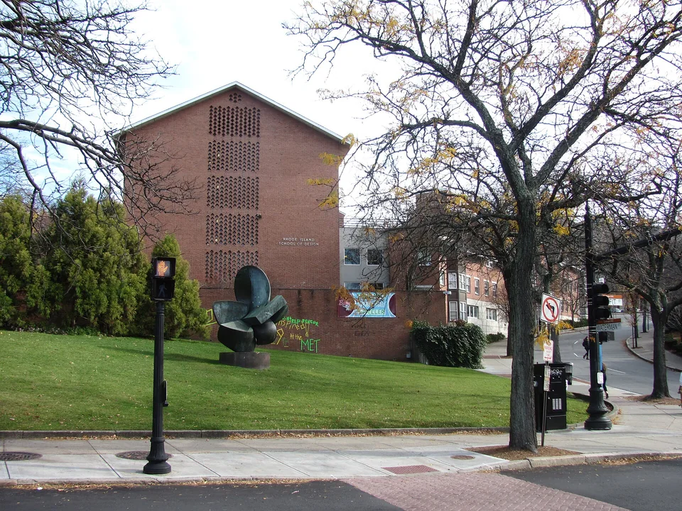 Кирпичный корпус с ажурной кладкой и надписью Rhode Island School of Design, перед ним газон с бронзовой скульптурой и осенние деревья
