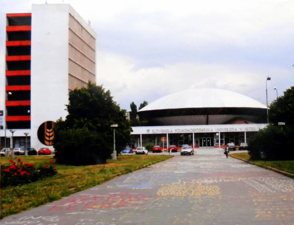 Аллея к зданию с куполом-«тарелкой» и надписью Slovenská poľnohospodárska univerzita v Nitre, слева высотный корпус с красными полосами